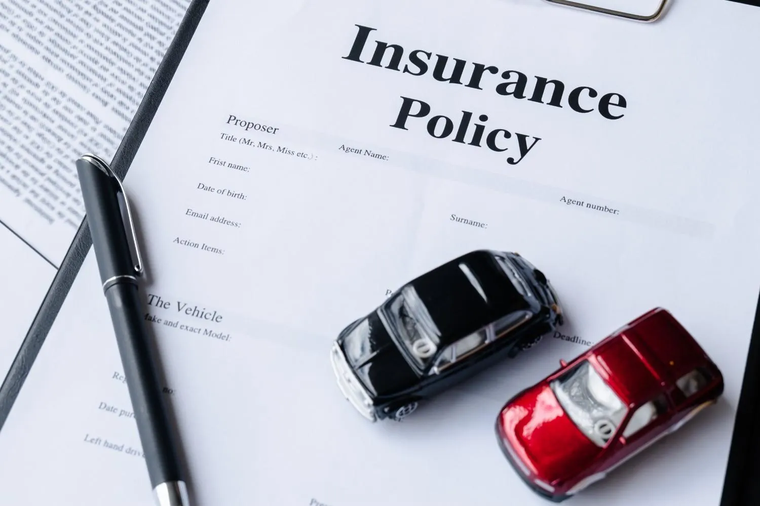 Driver reviewing car insurance paperwork beside a parked vehicle